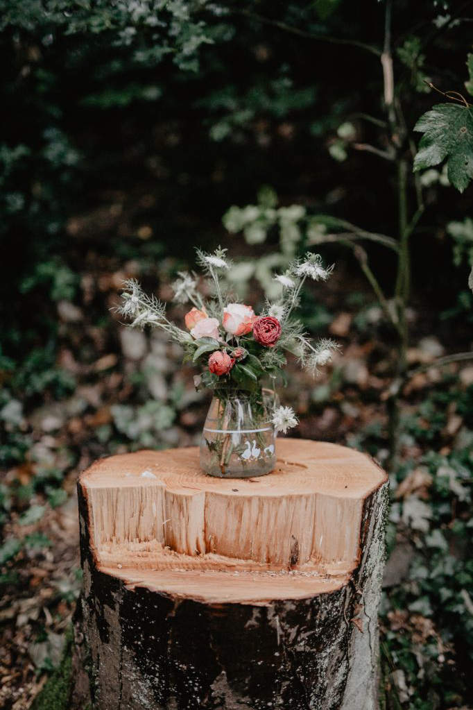 blumen in einer vase auf einem baumstumpf